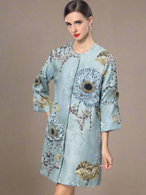 Light blue embroidered coat with floral patterns on a gray background